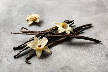 Bir yığın vanilya çubuğu ve arkaplanda çiçekler.