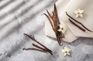 Arkaplanda vanilya çubukları, çiçekler ve tahtalar olan kompozisyon