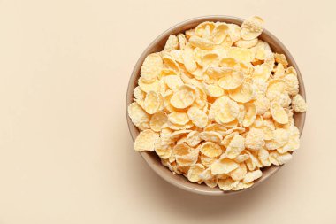 Bej arka planda lezzetli mısır gevrekleri olan kase, yakın plan.