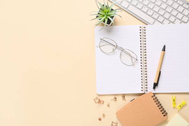 Bilgisayarlı klavye, gözlük ve bej arkaplan üzerinde farklı kırtasiye malzemeleri olan defterler