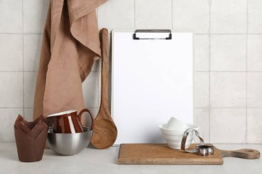 Farklı pişirme aletleri ve açık fayans duvarının yanındaki masada boş pano.