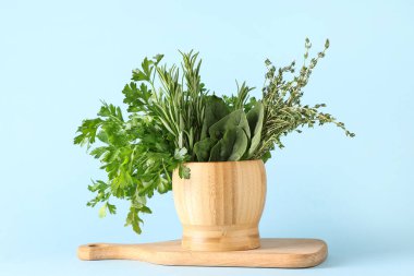 Ahşap havan mermisi ve farklı renklerde taze otlar.