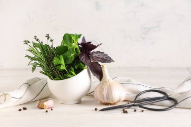 Taze bitkilerle, baharatlarla, makaslarla ve hafif ahşap masada peçeteyle havan topu.