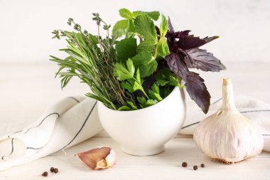 Taze bitkilerle, baharatlarla ve hafif ahşap masa üzerindeki peçeteyle havan topu.