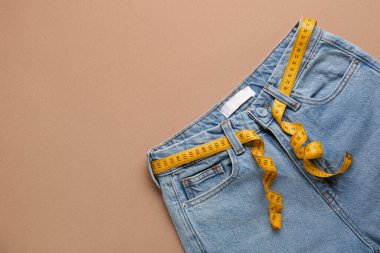 Kahverengi arka planda ölçü bandı olan kot pantolonlar. Anoreksi kavramı