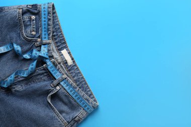 Mavi arka planda ölçü bandı olan kot pantolonlar. Anoreksi kavramı