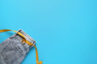 Mavi arka planda ölçüm bandı olan şık kot pantolonlar. Anoreksi kavramı