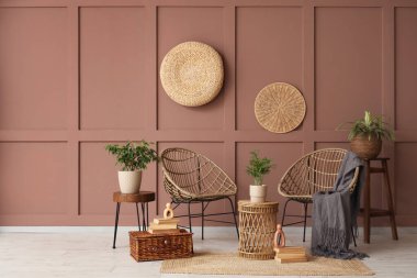 Hasır koltukları, masası ve bitkileri olan bir oda.