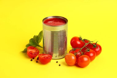 Sarı zemin üzerinde domates ezmesi olan teneke kutu.