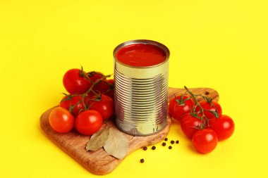 Domates ezmeli teneke kutu ve sarı arka planda malzemeler.