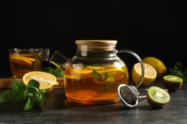 Siyah grunge masasında sıcak meyve çayı olan çaydanlık, yakın plan.