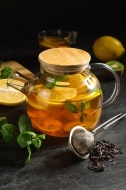 Siyah grunge masasında sıcak meyve çayı olan çaydanlık.