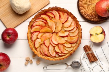 Tarçınlı elmalı turta ve beyaz ahşap arka planda çiğ hamur.