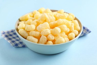 Mavi arka planda mısır çubukları olan bir kase.