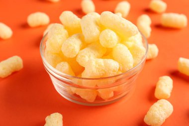 Turuncu arka planda tatlı mısır çubukları olan cam kase, yakın plan.