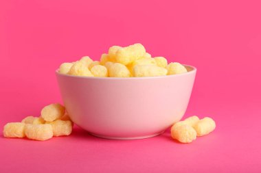 Pembe arka planda mısır çubukları olan bir kase.