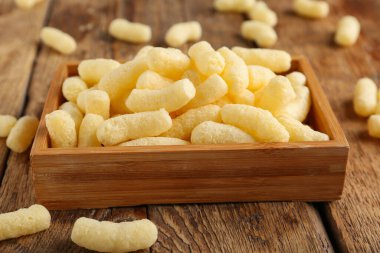 Tahta arka planda mısır çubukları olan kutu, yakın plan.