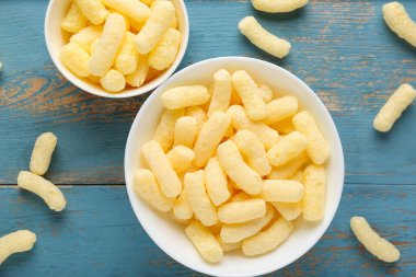 Mavi ahşap arka planda tatlı mısır çubukları olan kaseler.