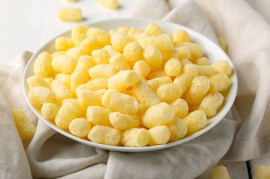 Beyaz ahşap arka planda tatlı mısır çubukları olan kase, yakın plan.