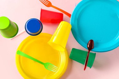 Pembe arka planda uçan renkli plastik sofra takımı