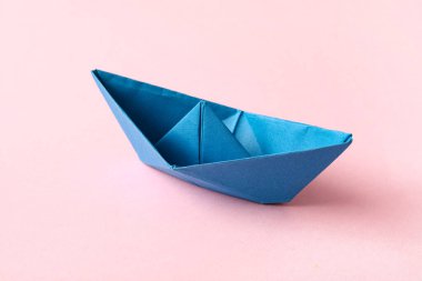Pembe arka planda mavi kağıt tekne