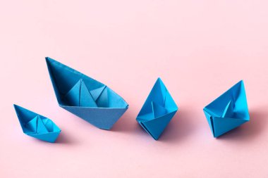 Pembe arka planda mavi kağıt tekneler