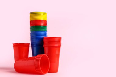 Pembe arka planda renkli plastik bardaklar