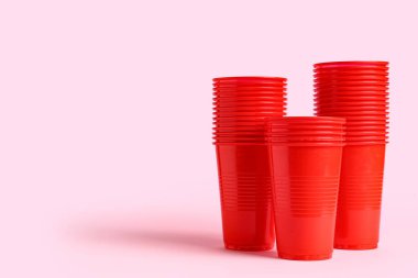 Pembe arka planda kırmızı plastik bardaklar