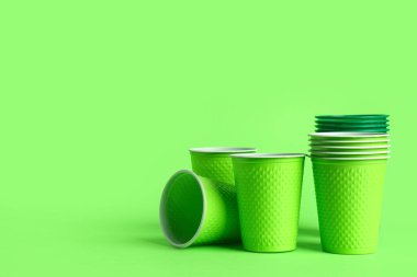 Renkli arkaplanda yeşil plastik bardaklar