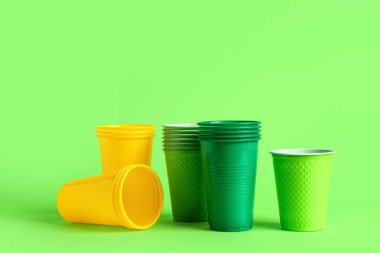 Yeşil arkaplanda farklı plastik bardaklar