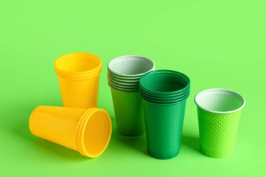 Yeşil arkaplanda farklı plastik bardaklar, yakın plan