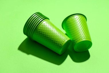 Renk arkaplanındaki yeşil plastik bardaklar, yakın plan