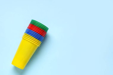 Mavi arkaplanda renkli plastik bardaklar