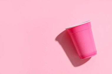 Renkli arka planda pembe plastik bardaklar