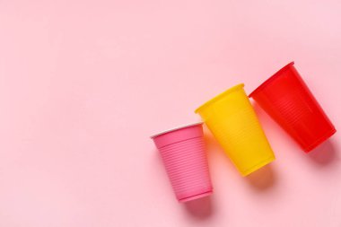 Pembe arka planda renkli plastik bardaklar