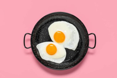 Pembe arka planda lezzetli kızarmış yumurtalı tava.