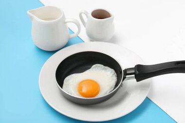Lezzetli kızarmış yumurta ve renkli arka planda sürahi sosla kızartma tavası, yakın plan.