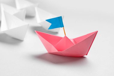 Biri bayraklı bir origami botu, diğeri de ışık arka planda. Liderlik kavramı