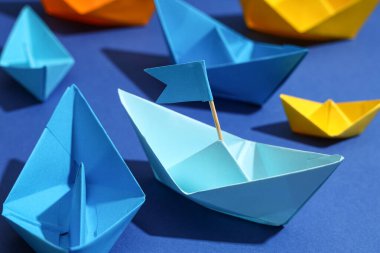 Mavi arka planda bayraklı bir origami teknesi, yakın plan. Liderlik kavramı