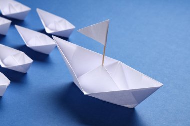 Mavi arka planda küçük bir origami teknesi. Liderlik kavramı