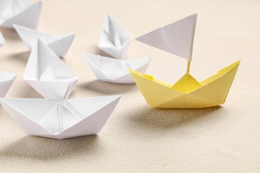 Bir sarı origami teknesi gri arka planda beyaz olanlar. Liderlik kavramı