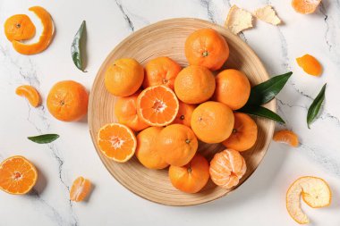 Beyaz arkaplanda tatlı mandalinalı ve yapraklı tabaklar