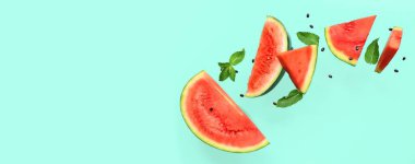 Uçan taze karpuz parçaları, nane ve tohumlar turkuaz arka planda ve metin için yer var