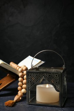 Müslüman lambası, yanan mum, Kuran ve koyu arkaplanda dua boncukları