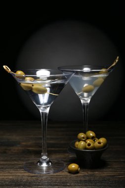 Lezzetli martiniler ve koyu ahşap masada zeytinler.