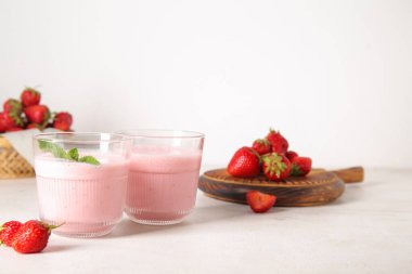 Hafif arkaplanda lezzetli çilekli smoothie bardakları
