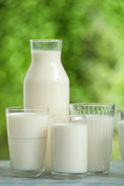 Mavi masada bardaklar ve bir şişe taze süt.