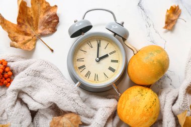 Alarm saati, balkabağı ve yapraklı sonbahar kompozisyonu beyaz arkaplanda