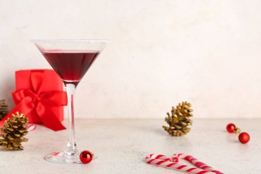 Masada beyaz grunge arka planında Noel süsü olan bir bardak lezzetli kırmızı margarita.