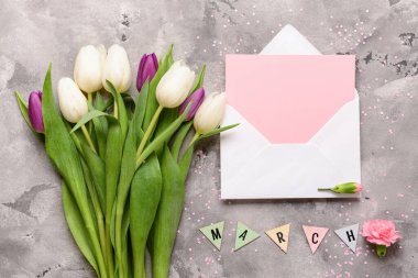 Üzerinde boş kart ve gri grunge arka planda lale çiçekleri olan zarf. Uluslararası Kadınlar Günü kutlamaları